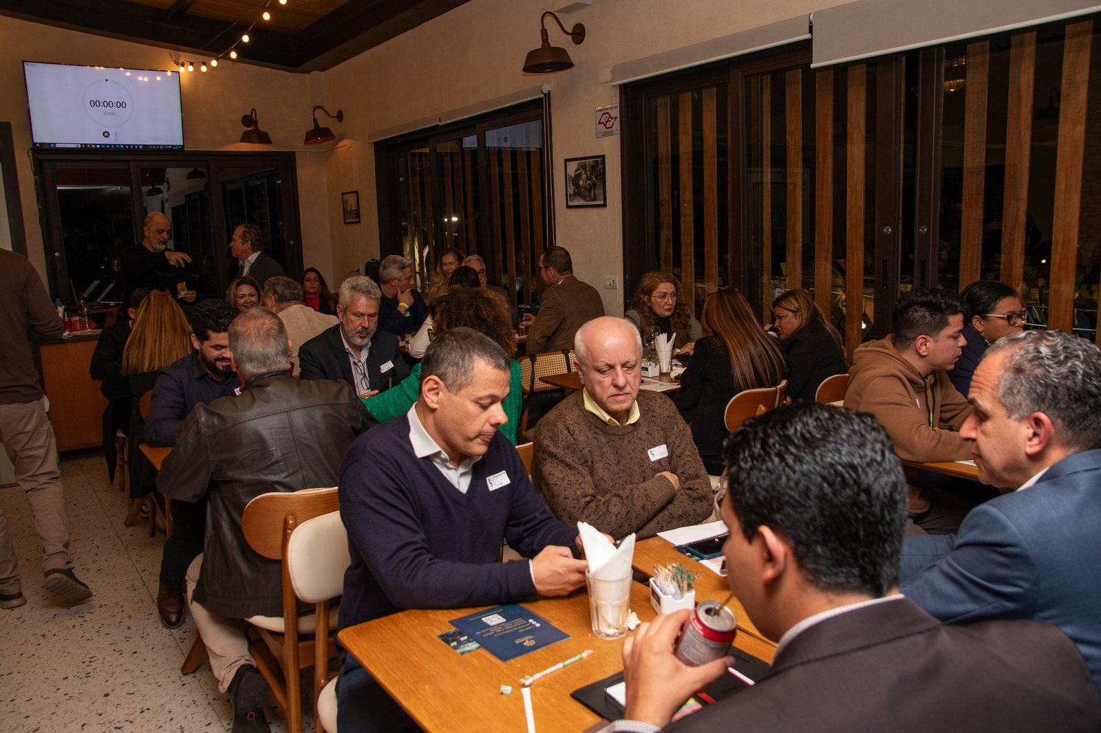 Empresários conversando em mesas durante encontro Networkers